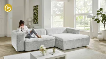 Frau sitzt entspannt auf einem Sofa und ließt ein Möbelmagazin